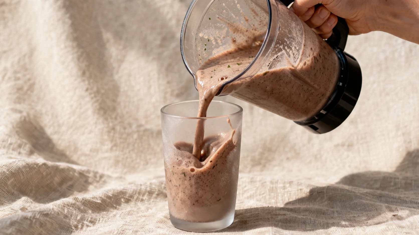 Milkshake chocolat-menthe protéiné servi dans un grand verre, décoré de menthe fraîche et de cacao en poudre