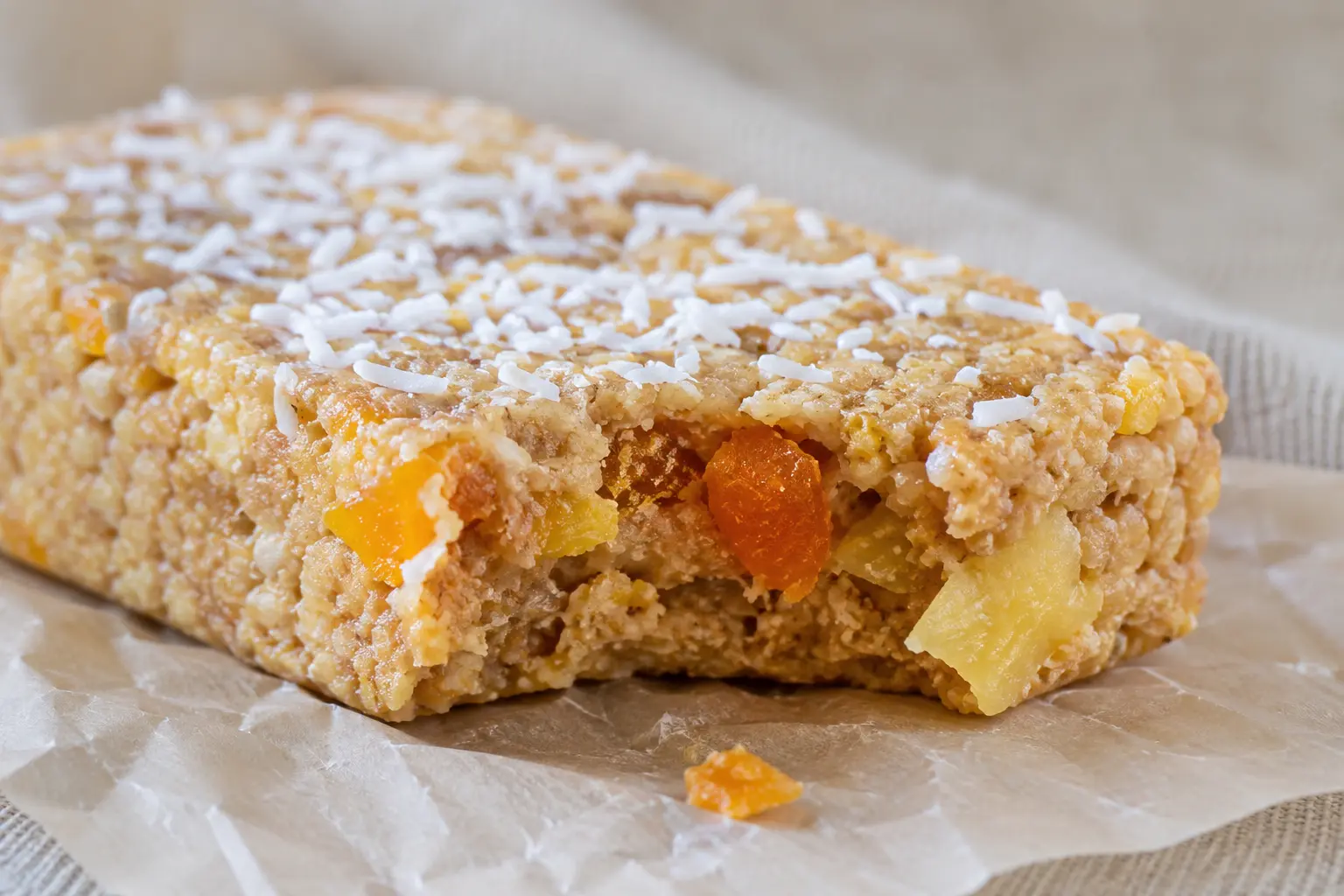 Gros plan sur une barre fruits exotiques protéinée montrant la texture avec morceaux de mangue et noix de coco