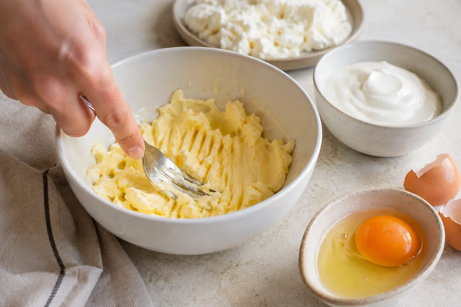Beurre ramolli travaillé à la fourchette avec fromage blanc et œuf dans un bol
