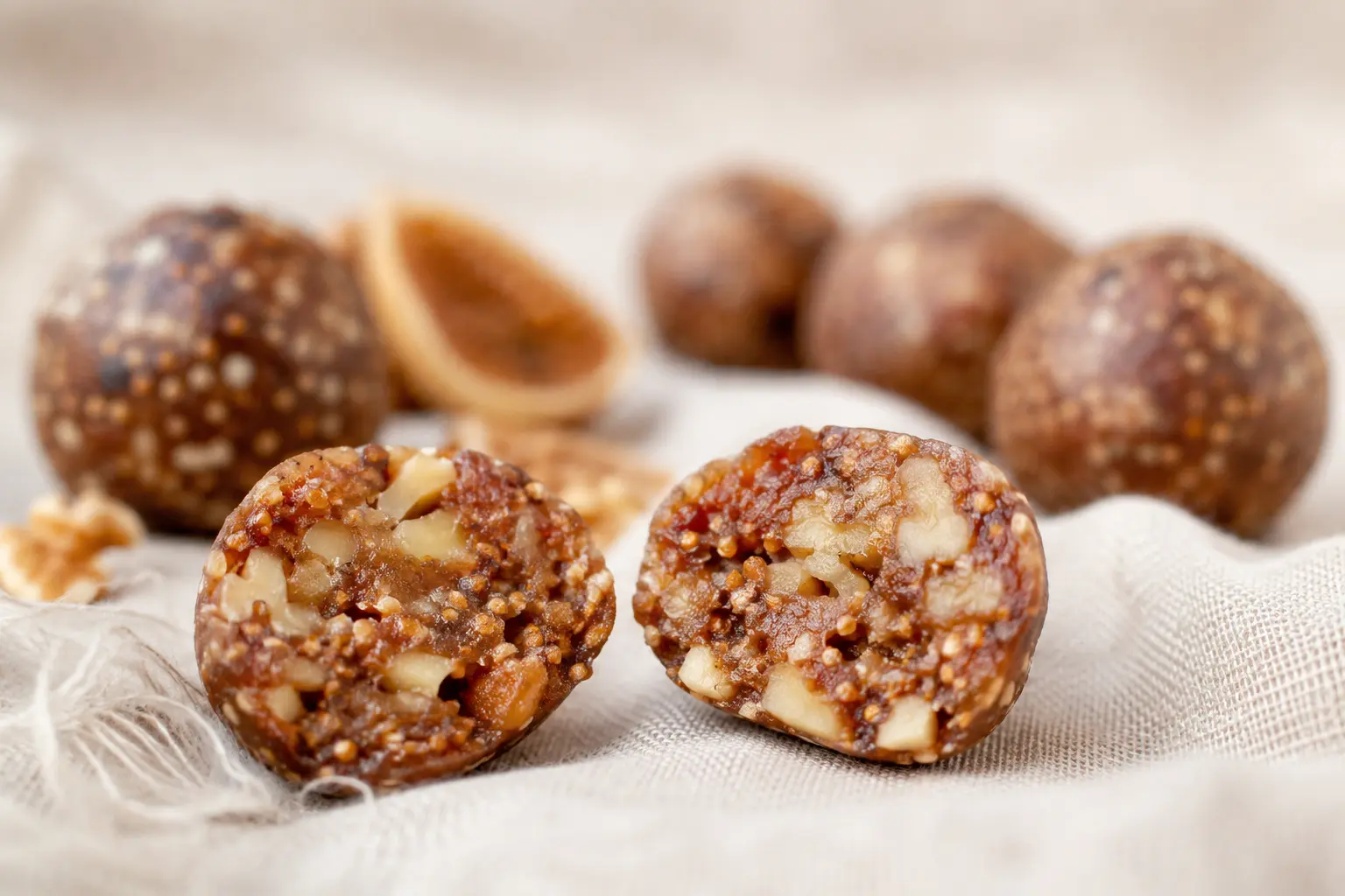 Gros plan sur une energy ball figues-noix coupée en deux montrant la texture moelleuse et les morceaux de noix
