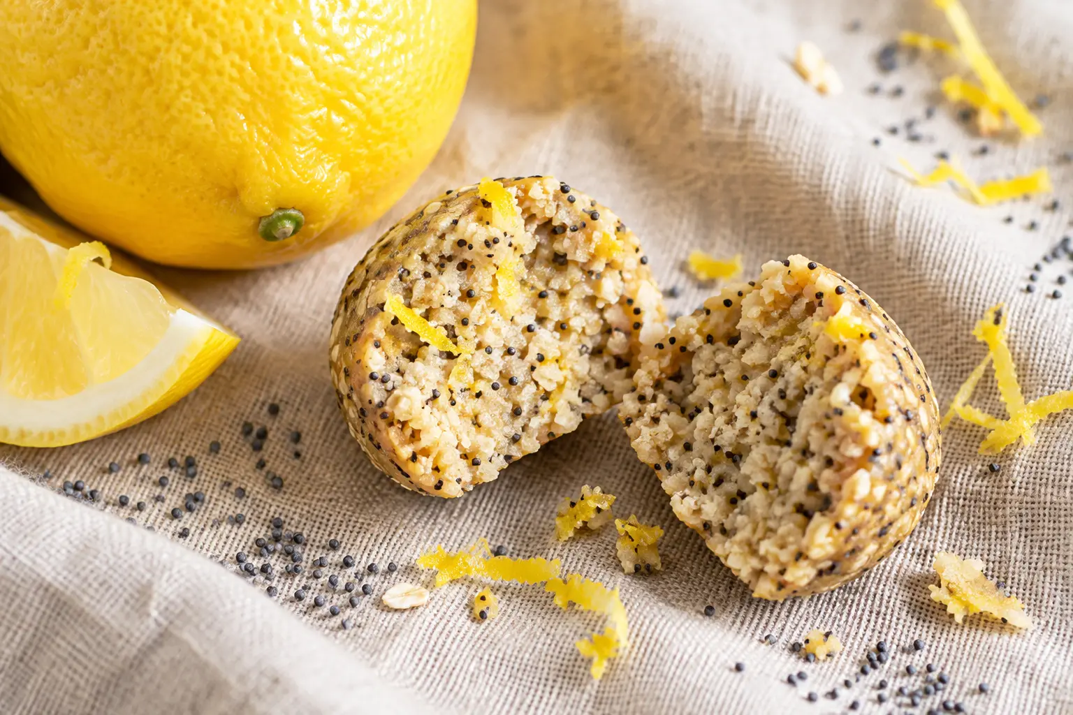 Gros plan sur une protein ball citron-pavot coupée en deux, montrant la texture intérieure fondante