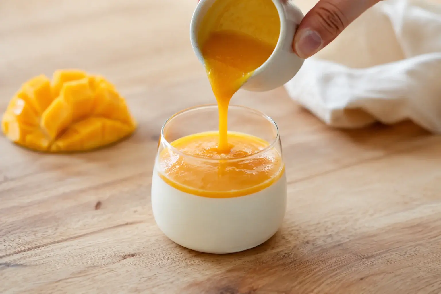 Panna cotta coco-mangue dressée avec coulis, noix de coco râpée et feuille de menthe