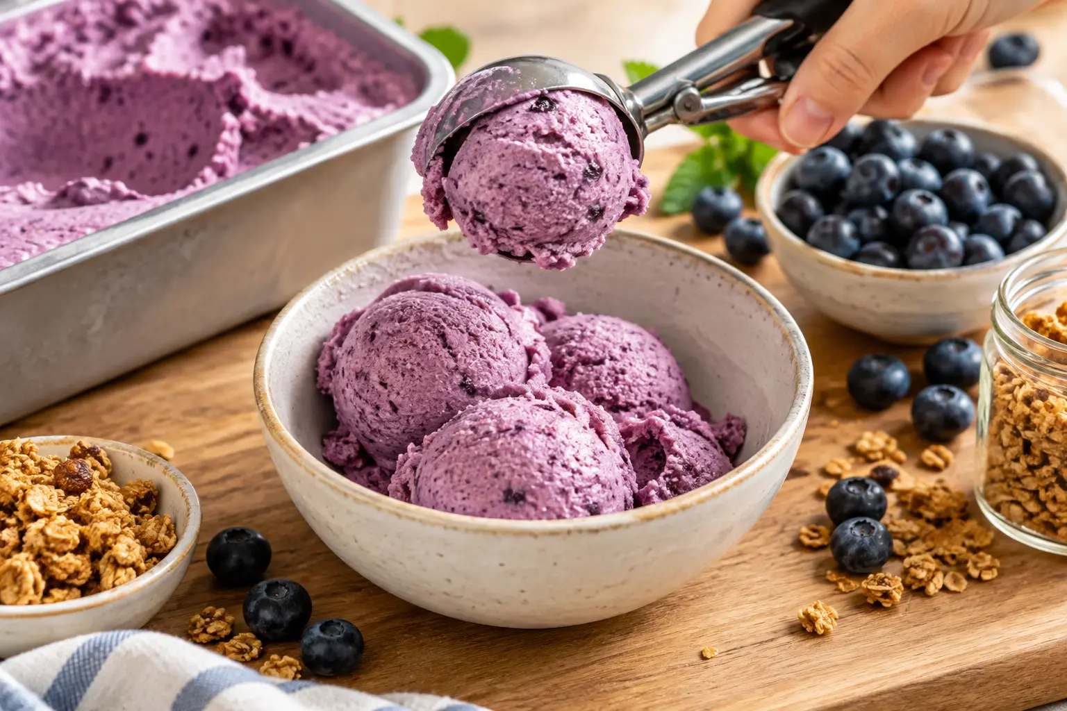 Boules de frozen yogurt myrtille servies dans un bol avec toppings de myrtilles et granola