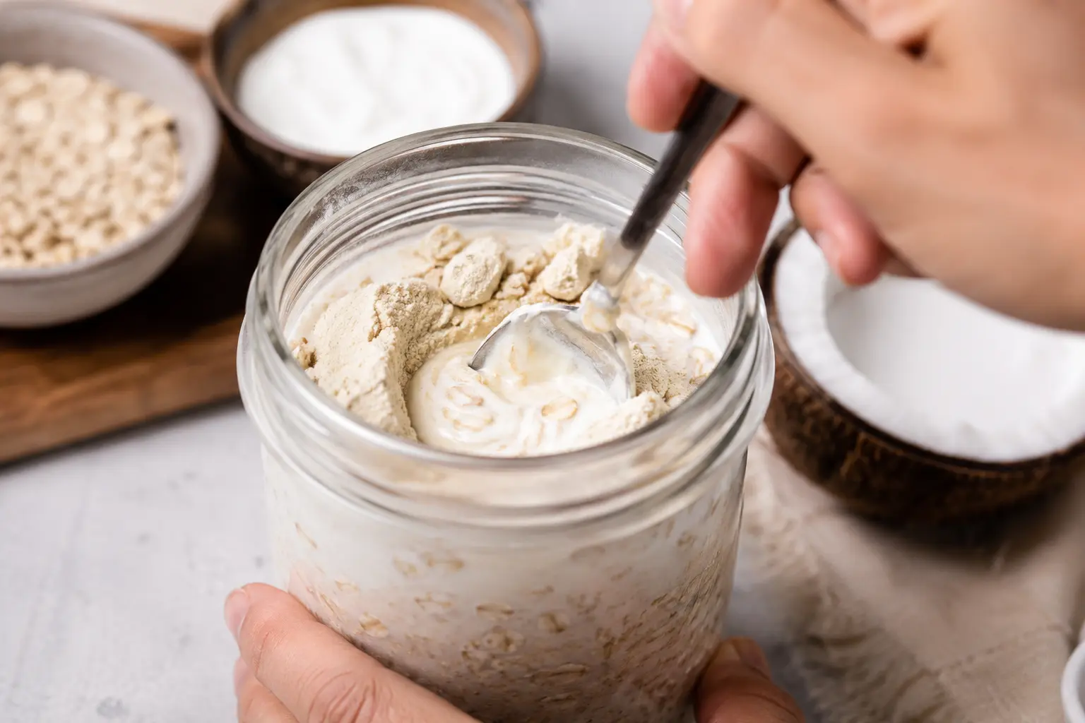 Mélange des flocons d'avoine avec le fromage blanc et le lait de coco dans un bocal