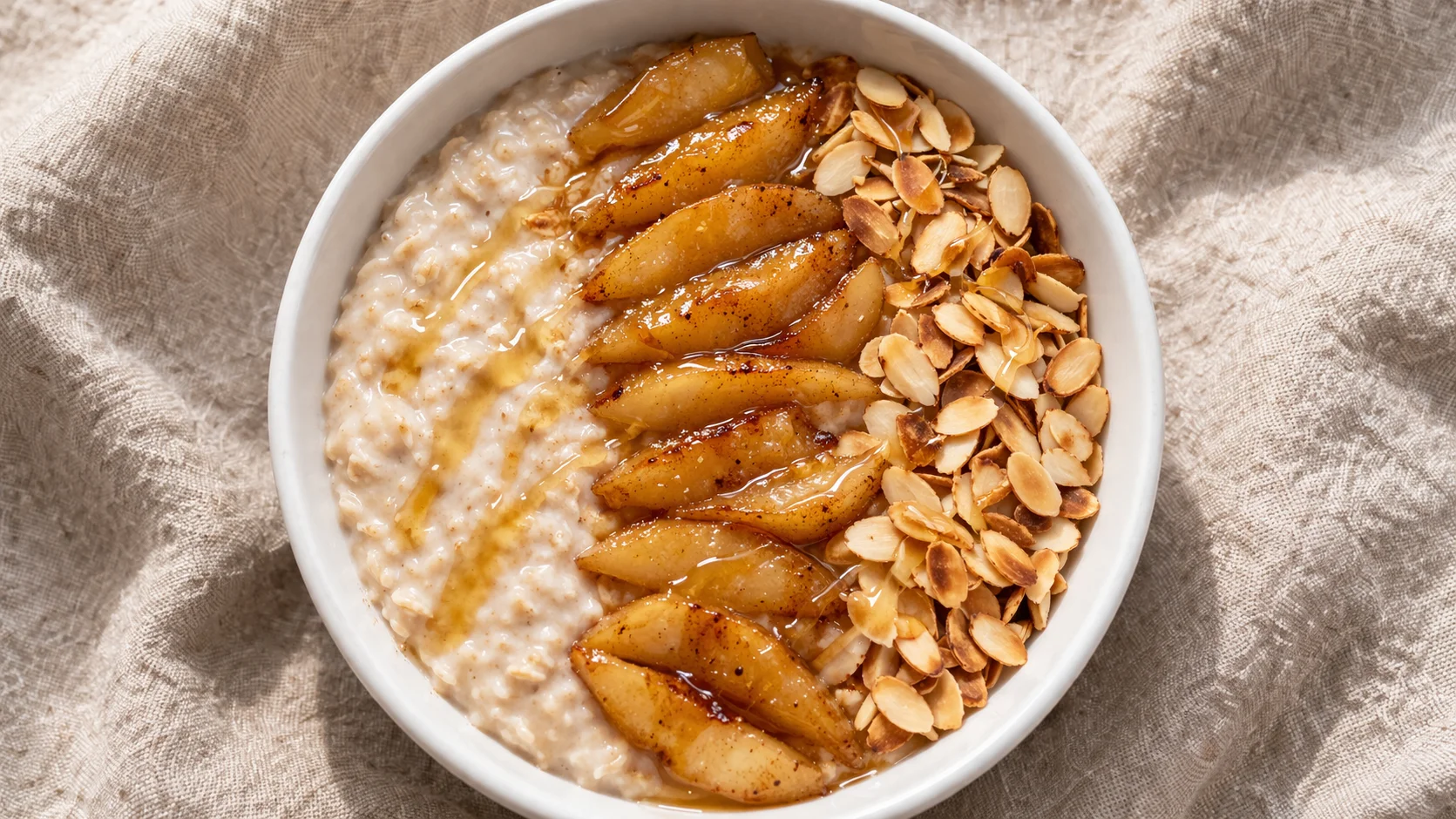 Gros plan sur la texture crémeuse du porridge avec dés de poire fondante et amandes dorées en surface