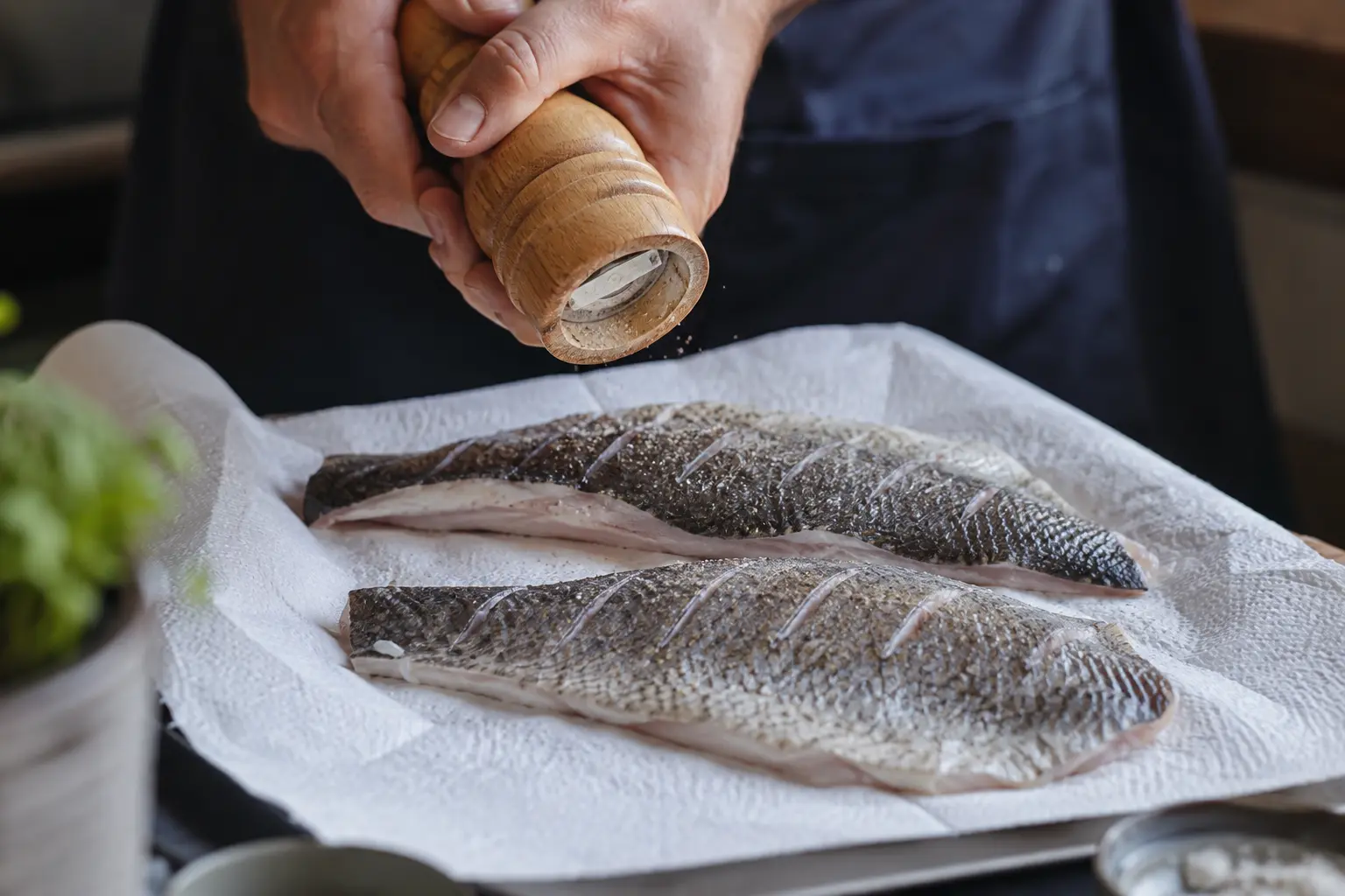 Filets de bar séchés et assaisonnés de sel et poivre sur une planche, peau incisée