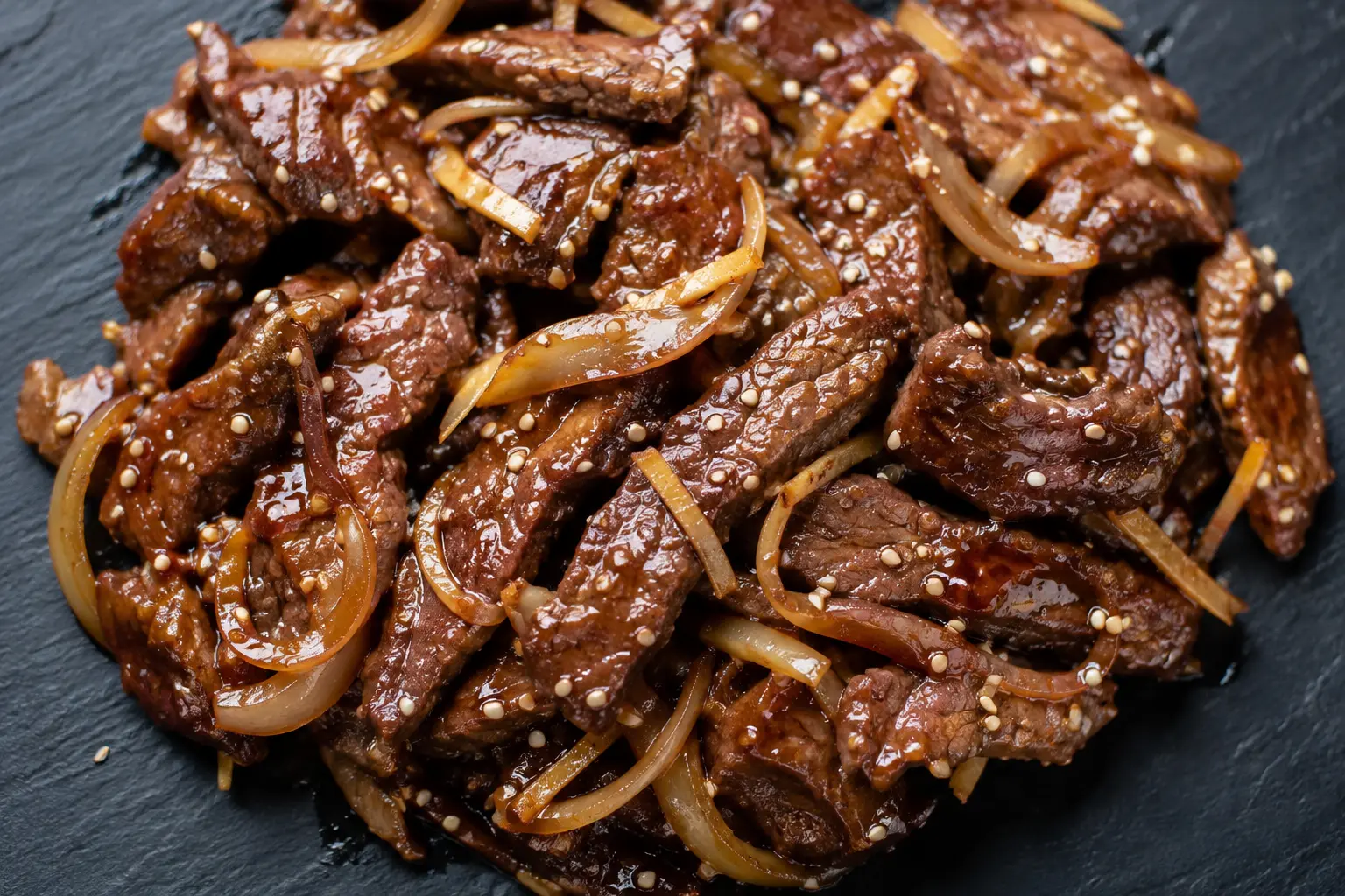 Gros plan sur les lamelles de bœuf sauté caramélisées aux oignons et gingembre