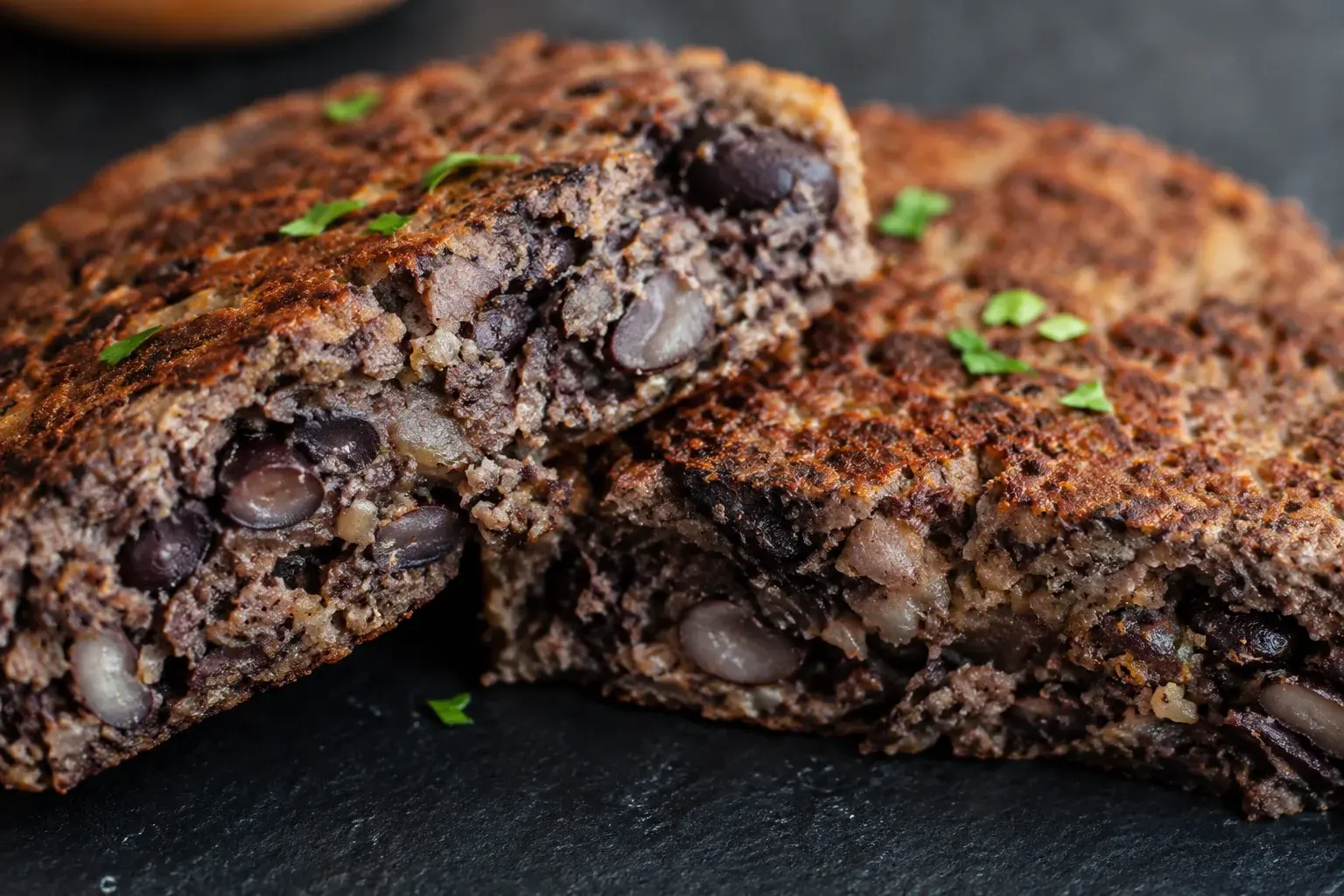 Gros plan sur la texture rustique d'un steak de haricots noirs avec morceaux entiers visibles et croûte dorée croustillante à la coupe