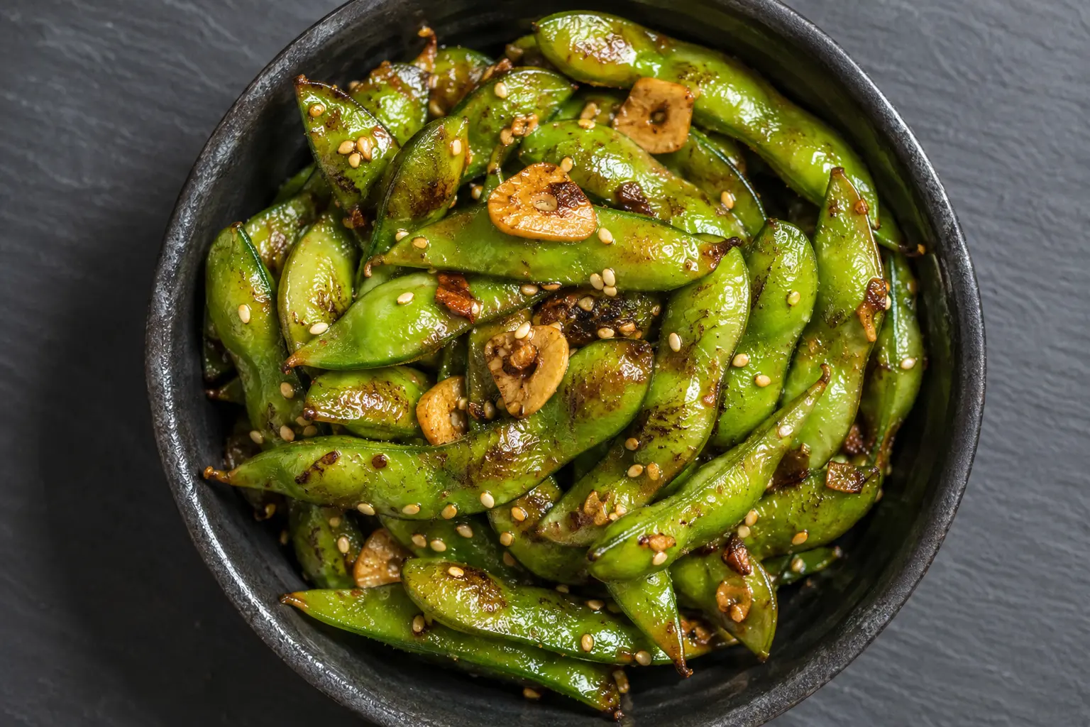 Gros plan sur des edamame sautés à l'ail parsemés de piment et sésame