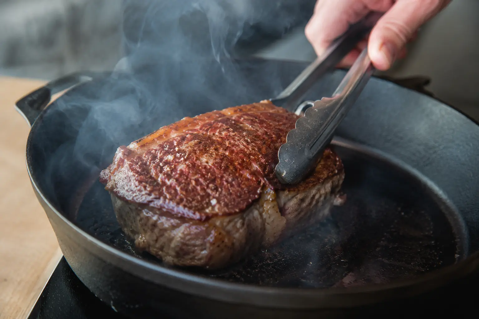 Steak de bœuf en train de saisir dans une poêle en fonte bien chaude